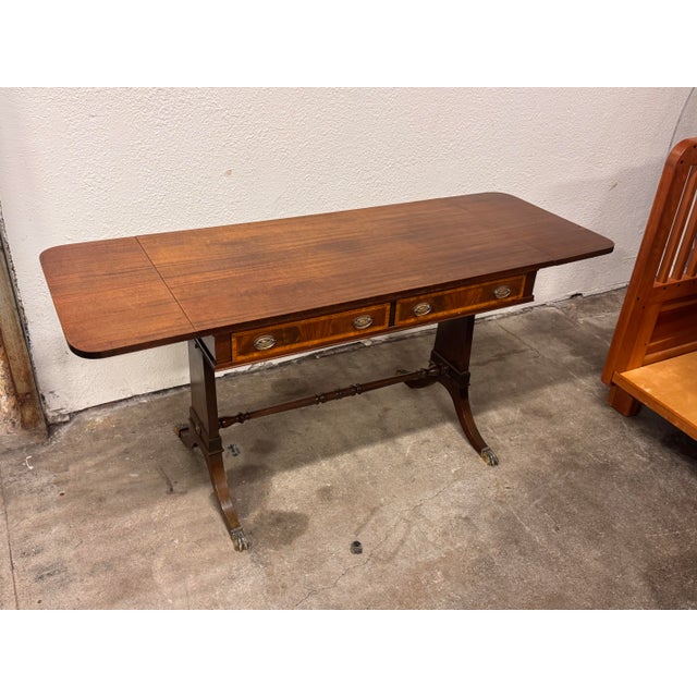 Design Plus Gallery presents a Regency Style Mahogany Drop-Leaf Desk. The desk has a rectangular top, rounded drop leaves,...