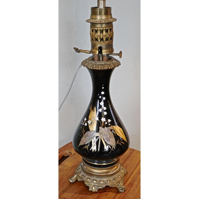 A pair of Victorian ceramic oil lamps decorated with Lilly of the valley. A beautiful pair of ceramic lamps set on brass...