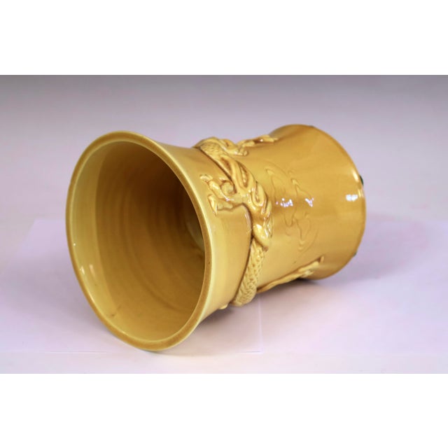 Awaji Pottery dragon vase or brush pot in yellow monochrome glaze, circa 1920. The dragon undulating horizontally through...