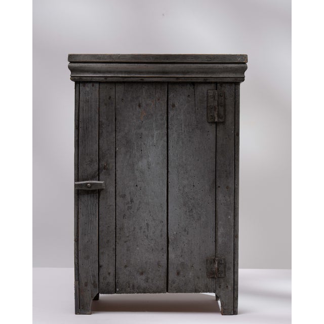 A simple and functional cabinet with a rustic aesthetic, emphasizing practicality over ornamentation. The aged wood and...