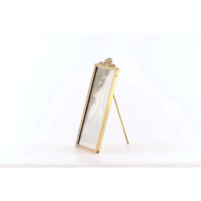 A vertically elongated rectangle desktop photo frame, decorated with an empire bow of gilded brass. Origin private...