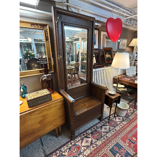 Handsome antique tiger oak hall tree having lift up seat with storage inside, original beveled mirror and charming brass...