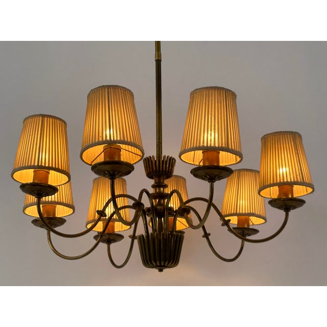 Extremely rare, elegant and highly decorative mid-century modern eight-armed brass chandelier or pendant lamp. Designed...