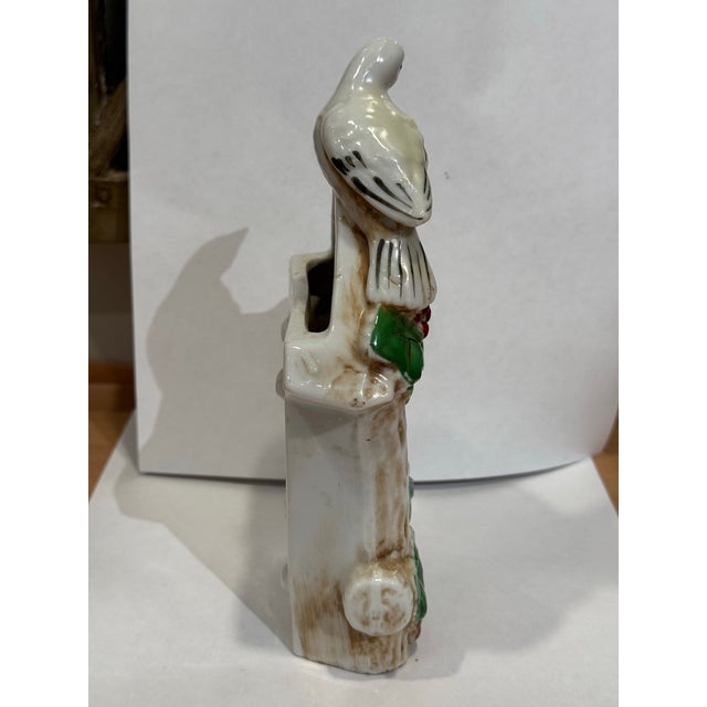 This is a mid 20th century vintage hand painted ceramic birdhouse clock figurine. It depicts a bird perched on a clock...