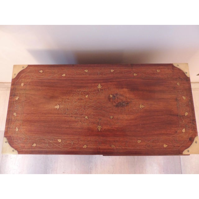 A vintage wooden campaign chest featuring brass inlaid metalwork and hardware. Inlaid metalwork features foliage design....