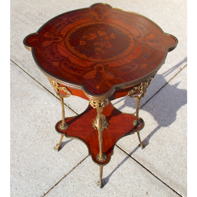 This antique French Louis XV style end table dates to the late 19th century and showcases the artistry of parquetry...