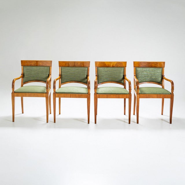A set of four elegant armchairs crafted from cherrywood in early 19th-century France. The chairs rest on tapered legs and...
