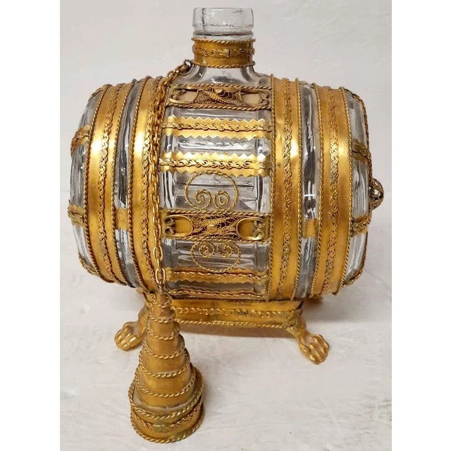 Am an unusual Bohemian glass and gold gilt metal decanter. Shaped like a barrel. Measures 9” tall, 6” wide and 3 1/2”...