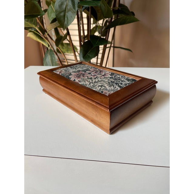 This jewelry box has an embedded floral tapestry on the lid and features a velvet lined interior and mirror. Measures 11”...
