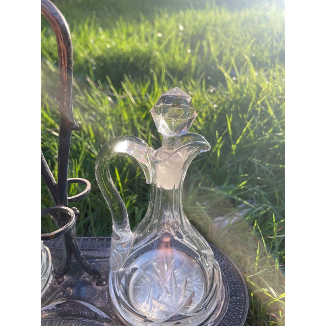 Elegant antique oil and vinegar cruet set featuring two matching cut crystal bottles with faceted stoppers, housed in a...