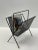 Great design in this Mid-Century Modern black iron magazine rack in the style of Hungarian artist, Mathieu Matégot.