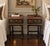 A charming pair of Chinoiserie-style nightstands featuring richly decorative Asian landscape scenes in warm gilt and...
