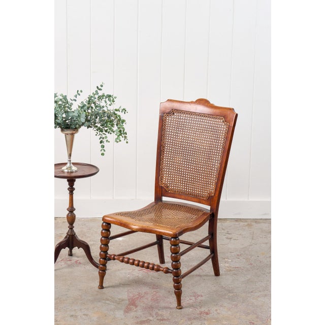 This antique petite walnut accent chair features a hand-tied cane seat and back, set against a rich patinaed walnut frame,...