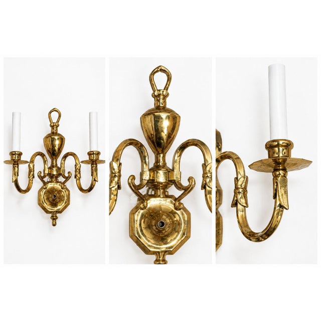 A charming vintage plated brass wall sconce with two curved arms, white candle-style lights, and beautiful antique...