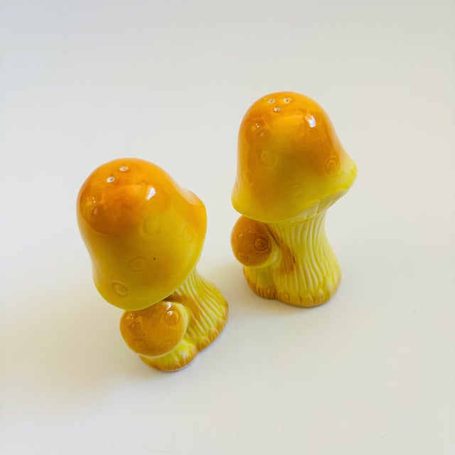 A pair of vintage ceramic salt and pepper shakers in the shape of mushrooms, each with a removable plastic stopper....