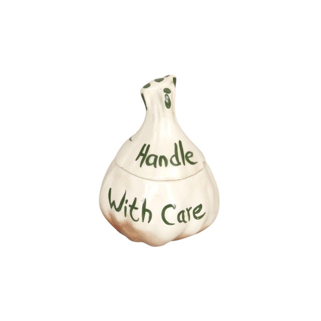 A Japanese ceramic garlic keeper jar with lid, circa 1960. Shaped like a bulb of garlic, the holder is anthropomorphic...