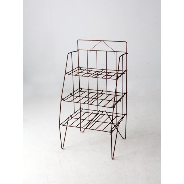 A vintage wire shelf rack with a collapsible frame and three open shelves, dating from the 1940s to 1950s. Its light, open...