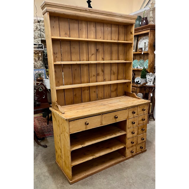 Antique English Pine. Two piece stepback cupboard. The base has open shelving in addition to a bank of 12 drawers. All...