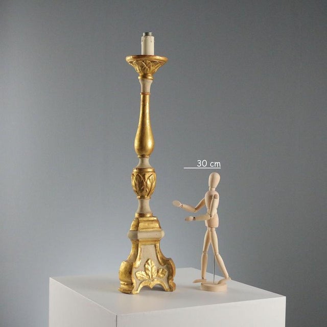 Carved and gilded wooden candelabra, featuring a turned central body that expresses the elegance and refinement typical of...
