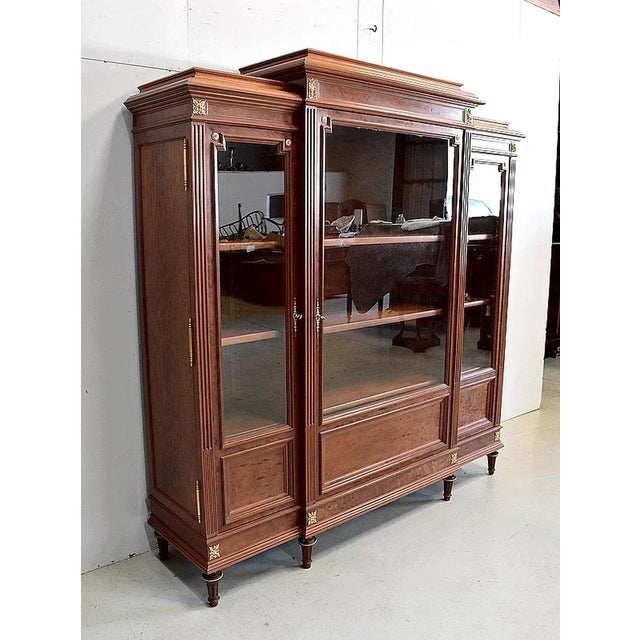 Charming Louis XVI style bookcase, with solid mahogany structure and mahogany veneer. It opens with three glass doors on...