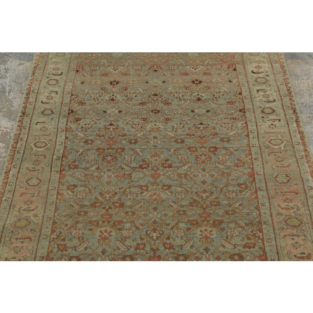 Hand-knotted in wool, circa 1900-1920, this distressed antique 3x18 Persian Bidjar runner features a floral geometric...