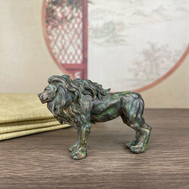 This detailed bronze sculpture depicts a majestic male lion captured in a dynamic, striding pose. The lion is finely...
