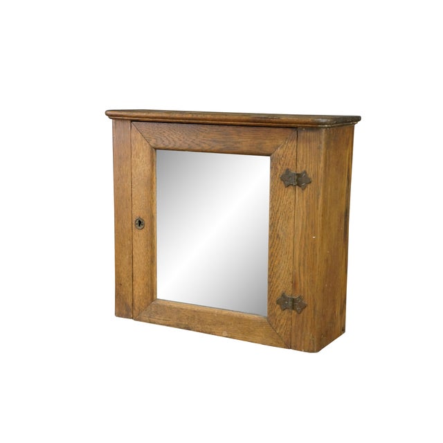 An early 20th century wall-mounted oak bathroom medicine cabinet. Blending a simple, rustic exterior with a deeply unique,...