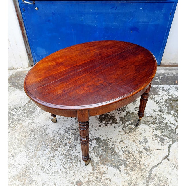 English extendable mahogany table with casters made at the end of the 19th century. The table has an oval shape and...
