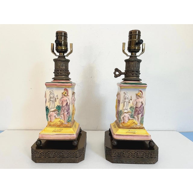 Gorgeous pair of 1940s glazed porcelain lamps in classical Roman style with hand painted dimensional mythological figures...