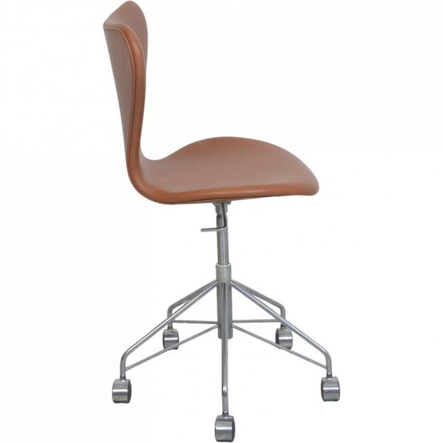 Arne Jacobsen office chair model 3117 upholstered in cognac classic semi anilin leather, and with a chrome frame. The...