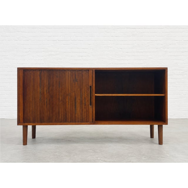 Mid Century Modern Danish rosewood sideboard featuring a tambour door and open shelving, c. 1960’s. This piece offers a...