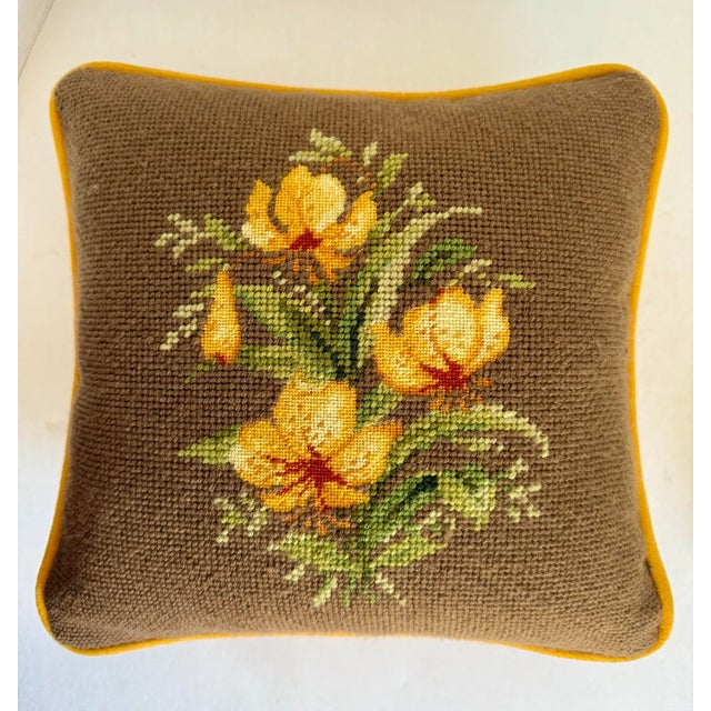 This charming vintage needlepoint pillow features a hand-stitched floral bouquet in warm yellows with sienna accents, and...