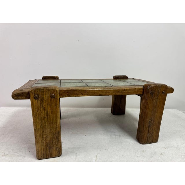A substantial brutalist coffee table with tiled top, dating to the 1960s–70s, notable for its weight, texture and...