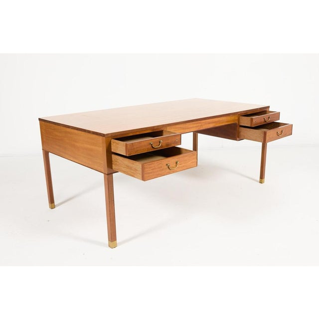 A Jacob Kjaer mahogany desk produced in 1950’s Denmark. It features 4 drawers with brass handgrips, pull out plate for...