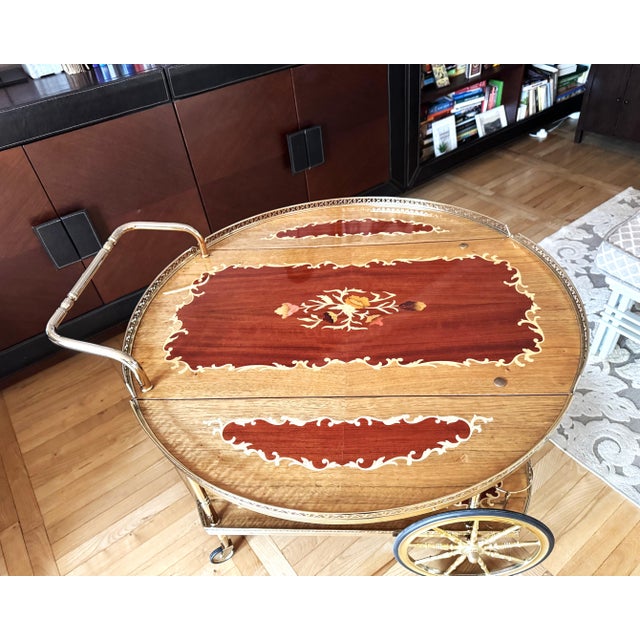 An elegant vintage drinks trolley crafted in the Italian Hollywood Regency style, combining polished brass with...