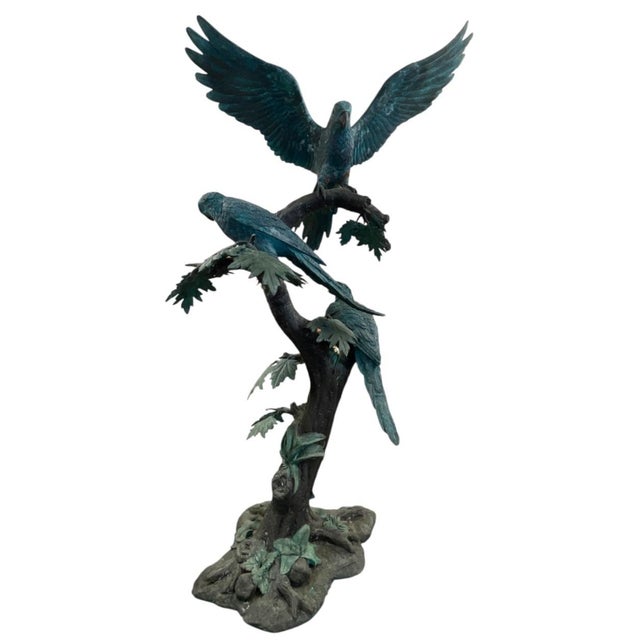This monumental bronze sculpture is a masterwork of decorative metalwork, capturing three detailed parrots perched amidst...