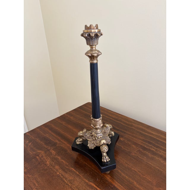 A gorgeous grand tour or neoclassical style brass and black candlestick holder with lion paw feet USA, Late 20th Century...