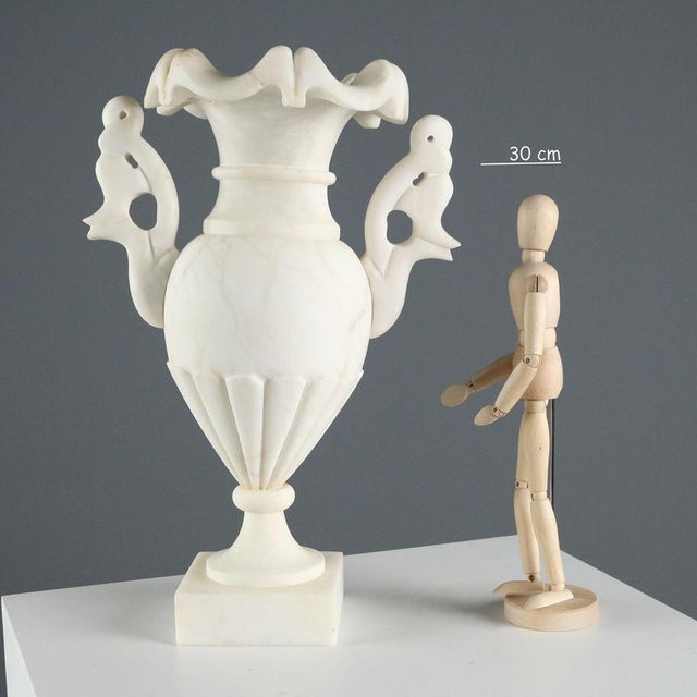 Electrified alabaster vase. It features an amphora-shaped central body embellished with large carved handles and a...