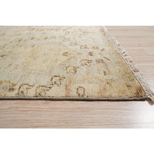 This ivory and beige wool rug features a hand knotted pile construction that highlights a sophisticated neutral palette....