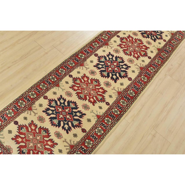 A traditional tribal Caucasian Kazak runner hand-knotted with fine wool on a cotton foundation. This rug features a row of...