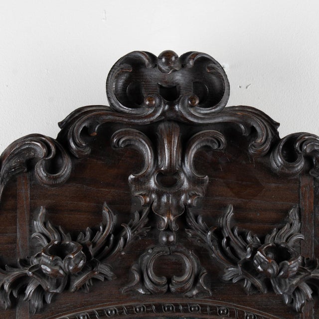 Early 20th century carved oval mirror from Portugal, crafted in oak. Highly decorative carving accentuates the frame, with...