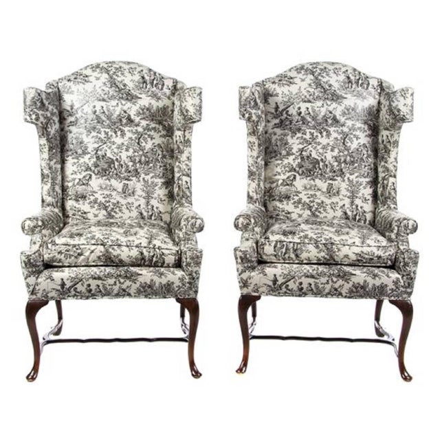 A pair of George III style wingback armchairs, Early 20th century. Each with glazed chintz toile upholstery, raised on...