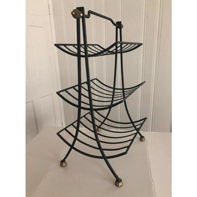 Lovely vintage tiered magazine rack or possible firewood caddy. Made of solid black wrought iron with brass-finished...