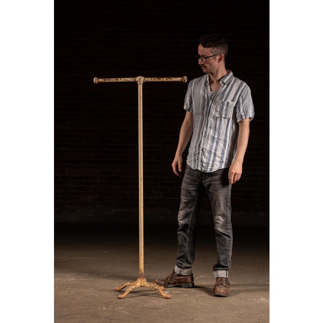 Freestanding industrial garment or display rack constructed from tubular steel with a heavy cast iron four-leg base and...