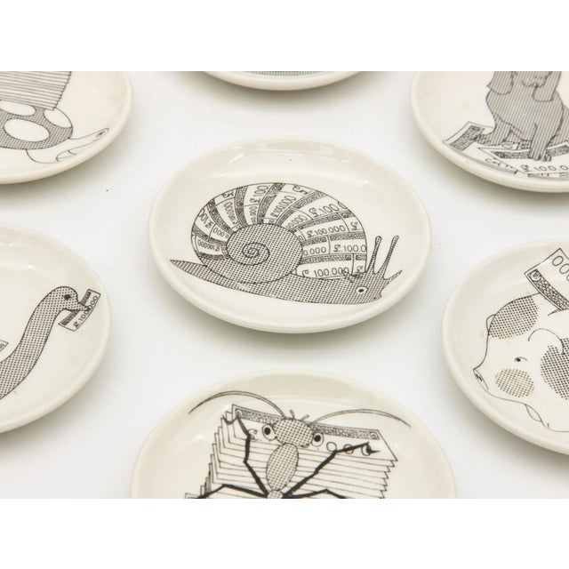 Set of seven black and white Fornasetti coasters featuring a snail, piggy bank, dog, hen, turtle, duck, and an ant.