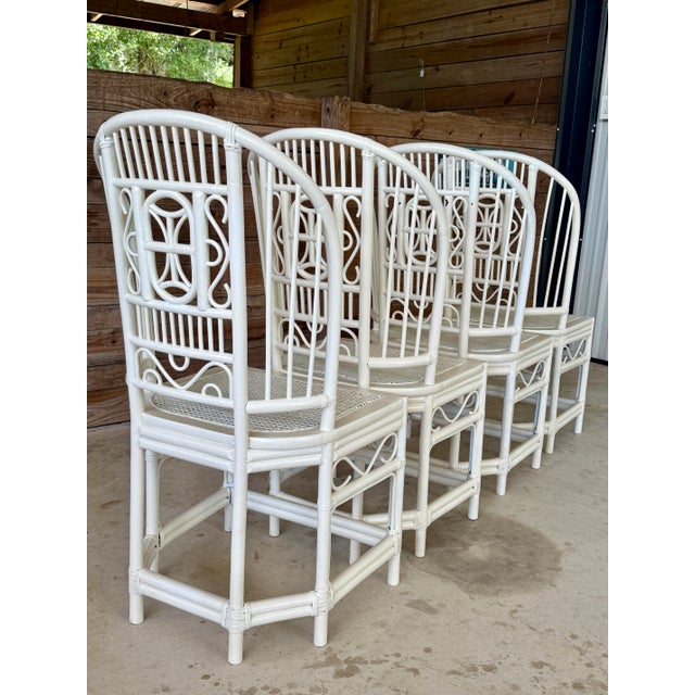 A charming pair of vintage high back rattan dining chairs featuring an intricate fretwork Chippendale-style design....