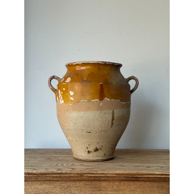 An extra-large French confit pot with a rich ochre glaze across the upper body, worn gracefully to reveal layers of...