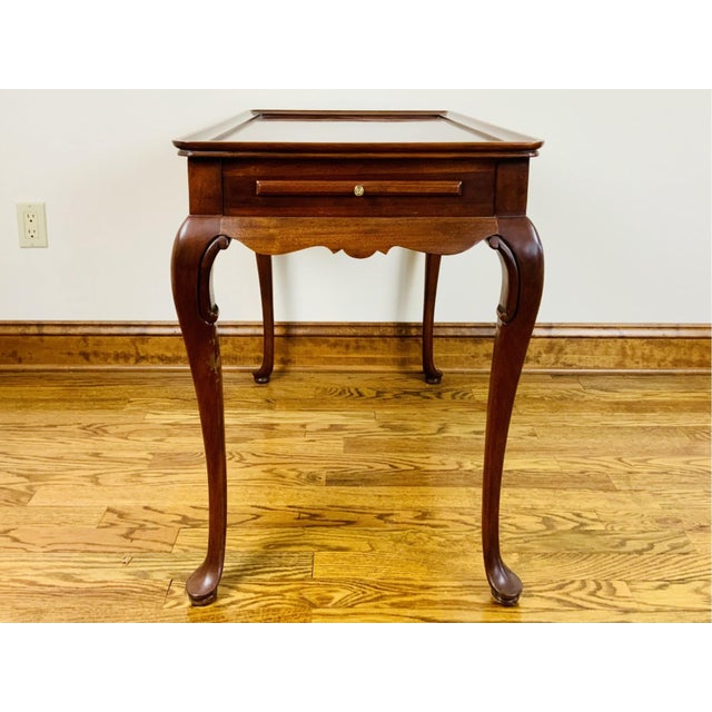 mahogany Queen Anne style tea table with a rectangular molded-edge gallery top, scalloped apron, pull-out drinks tray,...