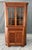 This antique bench-made burled walnut corner cabinet showcases rich figuring, glass-paneled upper doors for display, and a...