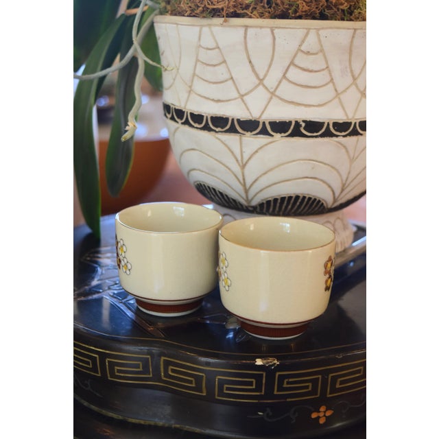 VINTAGE JAPANESE PORCELAIN TEA CUPS (PAIR) Era: 1960s-1970s Size: 3" diameter x 2.5" height OVERVIEW: A charming pair of...